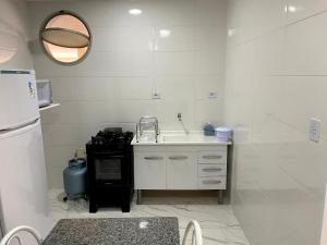uma pequena cozinha com um lavatório e um fogão em Studio na praia da ENSEADA no Guarujá