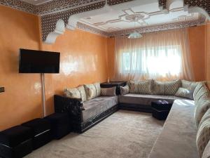 a living room with a couch and a tv at Villa Charaf in Agadir