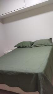 a bed with a green comforter in a room at CALDAS NOVAS - GO Apartamento Parque das Aguas Quentes bloco 3 - em frente Clube Privê in Caldas Novas