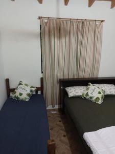 - une chambre avec 2 lits et une fenêtre avec des rideaux dans l'établissement Casa independiente amoblada en Capiata, à Capiatá