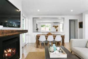 a living room with a fireplace and a table at Elysian Beach House Rye in Rye