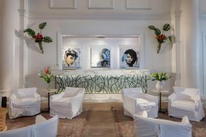 a room with white chairs and portraits on the wall at International House Hotel in New Orleans