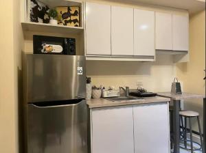 una cocina con nevera de acero inoxidable y armarios blancos en Sky Staycation KL Greenbelt, Isabel's Makati Rooms en Manila