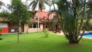 une maison avec une cour plantée de palmiers et une piscine dans l'établissement Flat Vila Caiçara, à Ilhabela