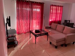 a living room with a couch and a table and red curtains at AJ resort in Fontein