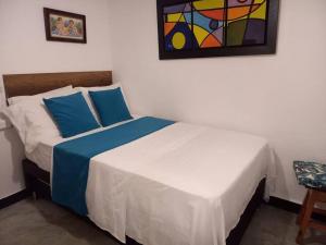 麥德林的住宿－Pioneros Poblado casa tradición，一间卧室配有一张带蓝色枕头的床和一幅画