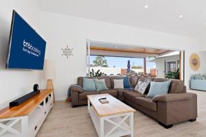 a living room with a couch and a tv at Mooloolaba Oasis 4bd Home, Pool in Mooloolaba