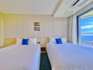 ソギポにあるHotel bridge Seogwipoのベッド2台 ホテルルーム 窓付