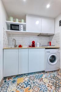 Alfama Rose Apartment في لشبونة: مطبخ بدولاب بيضاء وغسالة ملابس
