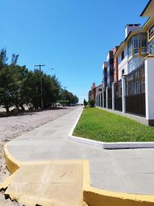 an empty sidewalk next to a street with buildings at Apartamento no condomínio Mediterranée- 3 quadras do mar- 1 dormitório em Capão Novo in Capão da Canoa