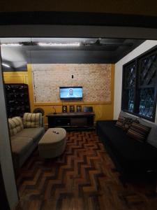 ein Wohnzimmer mit einem Sofa und einem Flachbild-TV in der Unterkunft Youkoso Hostel in Florianópolis