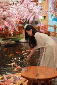 a woman is looking at a koi in a pond at KoiKing Homestay Quy Nhơn in Quy Nhon