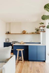 a kitchen with blue cabinets and a wooden stool at StowAway Kangaroo Island in Stokes Bay