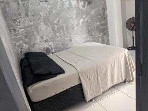 a bed with white sheets and black pillows on it at Youkoso Hostel in Florianópolis