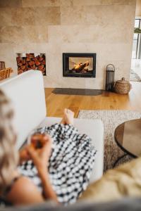 a woman sitting on a couch in a living room with a fireplace at StowAway Kangaroo Island in Stokes Bay