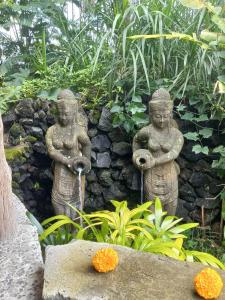 two stone statues standing next to a stone wall at Geopark Village & Spa in Kintamani
