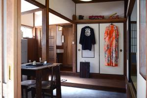 a room with a table and a coat hanging on a wall at ZOKUIJINKAN GUESTHOUSe 続異人館 in Arita