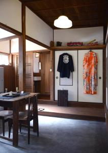 a dining room with a table and clothes hanging on a wall at ZOKUIJINKAN GUESTHOUSe 続異人館 in Arita