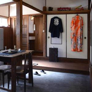 a room with a table and a dress hanging on a wall at ZOKUIJINKAN GUESTHOUSe 続異人館 in Arita