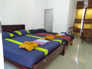 two beds in a room with yellow and blue sheets at Selahn Inn in Katunayake