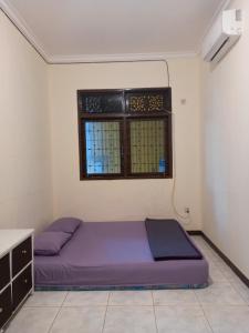 een slaapkamer met een paars bed en een raam bij COZY TO STAY TEBET (PENGINAPAN MURAH,TP GA MURAHAN) in Jakarta