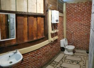 a brick bathroom with a sink and a toilet at Canyon Jungle Stay in Bukittinggi