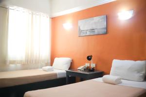 una camera d'albergo con due letti e una TV a parete di Ialodge a Ormoc