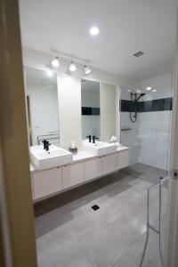 a white bathroom with two sinks and a shower at Melbourne Holiday Apartments Flinders Wharf in Melbourne