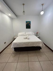 ein weißes Schlafzimmer mit einem Bett mit zwei Handtüchern darauf in der Unterkunft Casa Calas in Alajuela