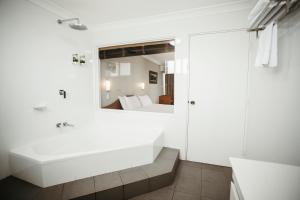 uma casa de banho com uma banheira branca e um espelho. em Colonial Motel Richmond em Richmond