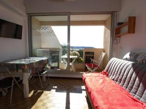 ein Wohnzimmer mit einem Sofa und einem Tisch sowie einem Balkon in der Unterkunft Appartement Balaruc-les-Bains, 1 pièce, 2 personnes - FR-1-553-195 in Balaruc-les-Bains