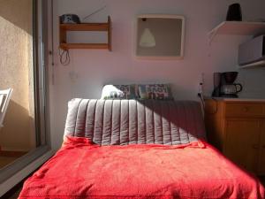 ein Schlafzimmer mit einem Bett mit einer roten Decke in der Unterkunft Appartement Balaruc-les-Bains, 1 pièce, 2 personnes - FR-1-553-195 in Balaruc-les-Bains
