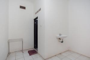 La salle de bains est pourvue d'un lavabo et d'un mur blanc. dans l'établissement RedDoorz Syariah Plus near Jatiwarna Toll Gate, à Bekasi