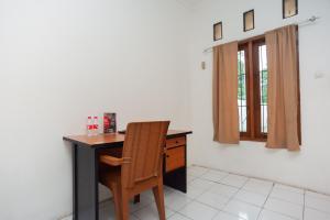 einen Schreibtisch mit Stuhl in einem Zimmer mit Fenster in der Unterkunft RedDoorz Syariah Plus near Jatiwarna Toll Gate in Bekasi