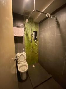 ein Bad mit einem WC und einer grünen Dusche in der Unterkunft OYO 90709 Northern Inn 