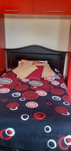 a bed with a black and red comforter on it at Casa N Campestre uno en las faldas de Taita Imbabura in Hacienda Chichavo