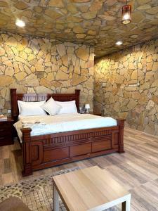 Cama en habitación con pared de piedra en jabal shams view stay نزل إطلالة جبل شمس en Al Ḩamrāʼ