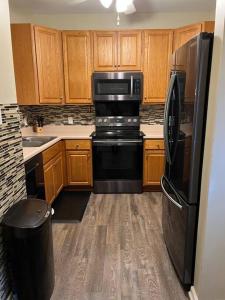 a kitchen with wooden cabinets and a black refrigerator at Cheerful 3 bedroom, close to downtown and arena!!! in Savannah