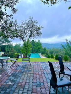 a patio with chairs and a table and a pool at Eco Village Yoga Home in Digana