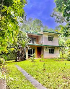 a yellow house with a grass yard in front of it at Eco Village Yoga Home in Digana