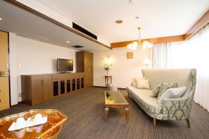 sala de estar con sofá y TV en Shohakuen Hotel, en Kitakyushu