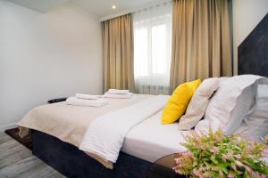 a bedroom with a bed with white sheets and yellow pillows at Светлая квартира in Almaty