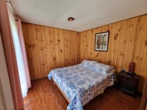 ein Schlafzimmer mit einem Bett und einer Holzwand in der Unterkunft Cabañas Villa Paradiso Salto del Laja in Los Ángeles