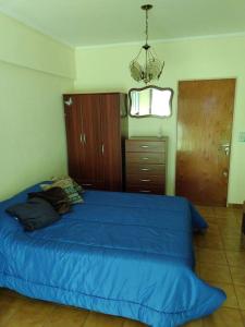Un dormitorio con una cama azul y una lámpara de araña. en La Perla en Mar del Plata