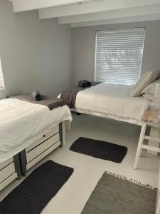 two beds in a room with two rugs and a window at Cozy Corner Cottage in Langebaan +29 photos