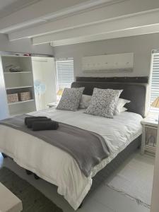 a bedroom with a large white bed with pillows at Cozy Corner Cottage in Langebaan