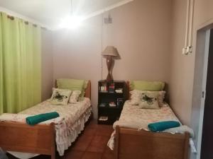 two beds in a small room with green curtains at Skaap Kraal Guest Farm in Kakamas