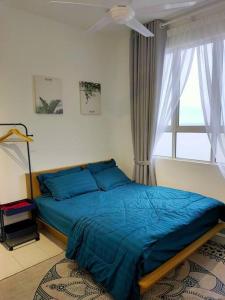 um quarto com uma cama com lençóis azuis e uma janela em Sofia Homes Kuala Terengganu em Kuala Terengganu