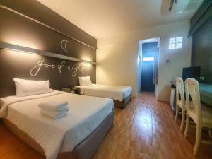 a hotel room with two beds and a sign that reads good night at BJ city hotel in Surat Thani