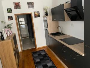 uma pequena cozinha com armários pretos e um lavatório em B&B bei Pepe Nero. em Sankt Pölten